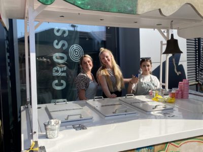 Gina's IJskar met enthousiaste ijsdames die ambachtelijk Italiaans schepijs serveren tijdens een evenement.